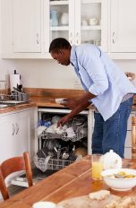 Eine Person räumt nach dem Frühstück Geschirr in eine Spülmaschine.