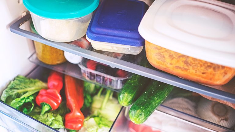 Mehrere Plastikboxen und ganz viel Gemüse in einem prall gefüllten Kühlschrank.