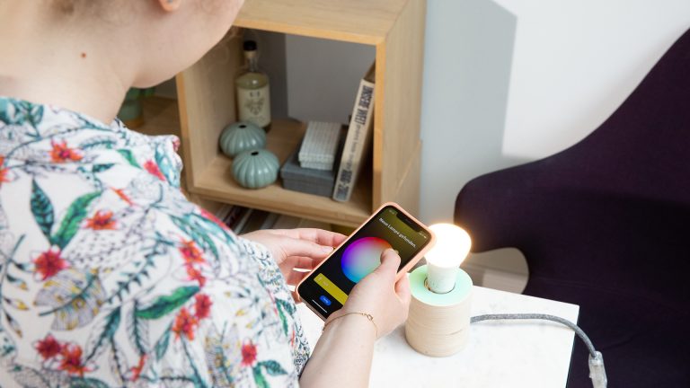 Eine Person stellt die Farbe einer smarten Lampe über die Philips Hue App auf Gelb ein.