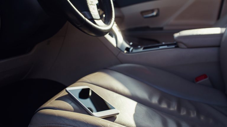 Ein Smartphone liegt auf dem Vordersitz eines Autos in direkter Sonneneinstrahlung.