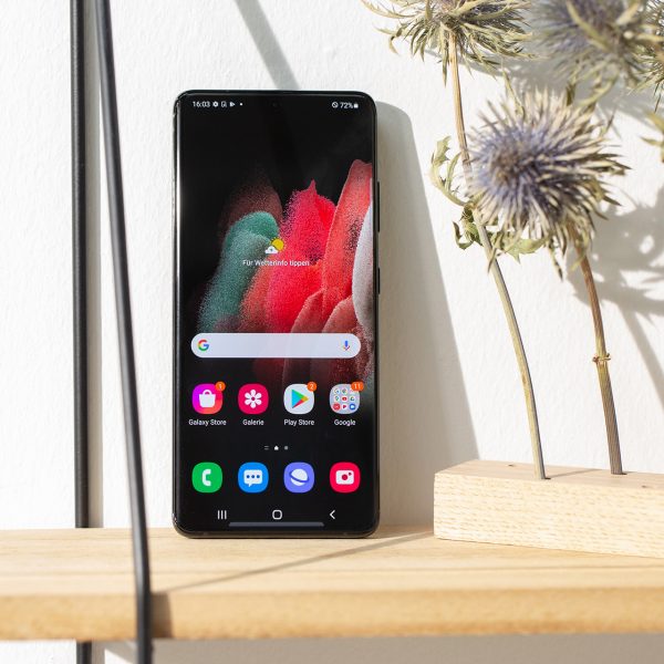 Das Samsung Galaxy S21 Ultra 5G steht auf einem Regal. Zu sehen ist der Home-Bildschirm.