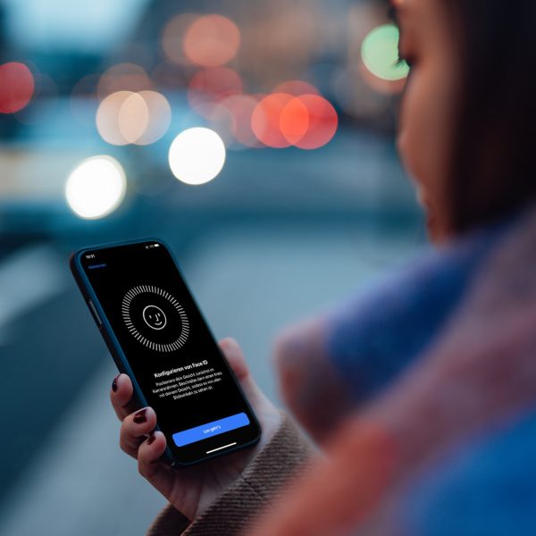 Eine Frau blickt auf ihr iPhone. Darauf ist die Einrichtung f&uuml;r Face ID zu sehen.