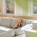 Eine Person sitzt auf einem Sofa. Von drau&szlig;en scheint die Sonne in den Raum.