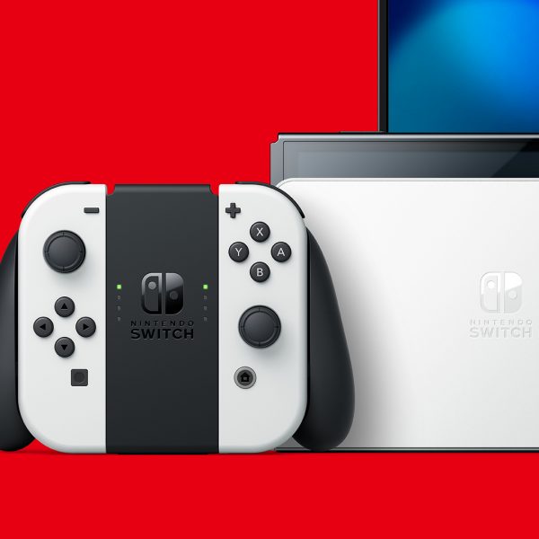 Aufnahme der Nintendo Switch OLED in der Dockingstation und der Joy-Cons in der Controller-Halterung vor einem roten Hintergrund.