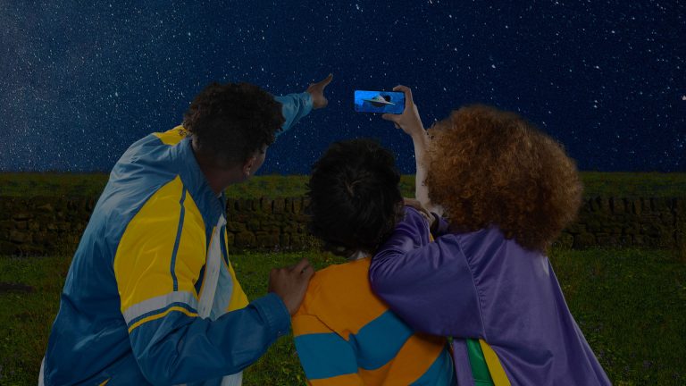Drei Personen halten ein OnePlus Nord 2 5G Richtung Sternenhimmel.