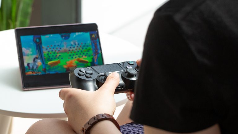 Eine Person hält einen PS4-Controller in der Hand und spielt ein Spiel vom Xbox Game Pass damit.