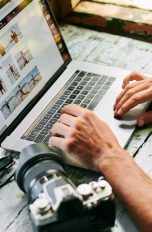 Bildbearbeitung am Mac Eine Person bearbeitet an einem MacBook Bilder nach. Daneben liegt eine Kamera.