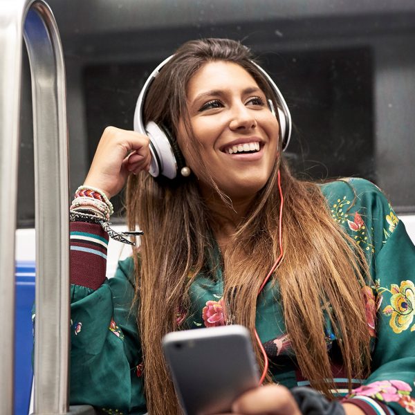 Eine Person fährt in der Bahn und hört dabei Musik von ihrem Smartphone.