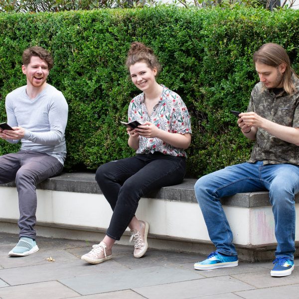 Drei Personen sitzen auf einer Bank und halten das Samsung Galaxy Z Fold2 und Z Flip in den H&auml;nden.