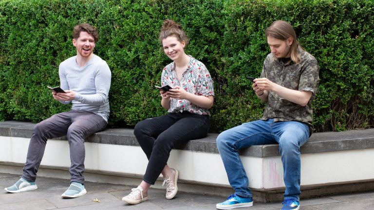Drei Personen sitzen auf einer Bank und halten das Samsung Galaxy Z Fold2 und Z Flip in den Händen.