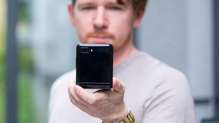 Eine Person hält ein halb aufgeklapptes Samsung Galaxy Z Flip in die Kamera.