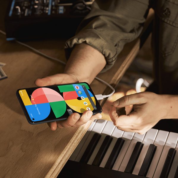 Eine Person h&auml;lt das Google Pixel 5a in der Hand, das per USB-C aufgeladen wird.
