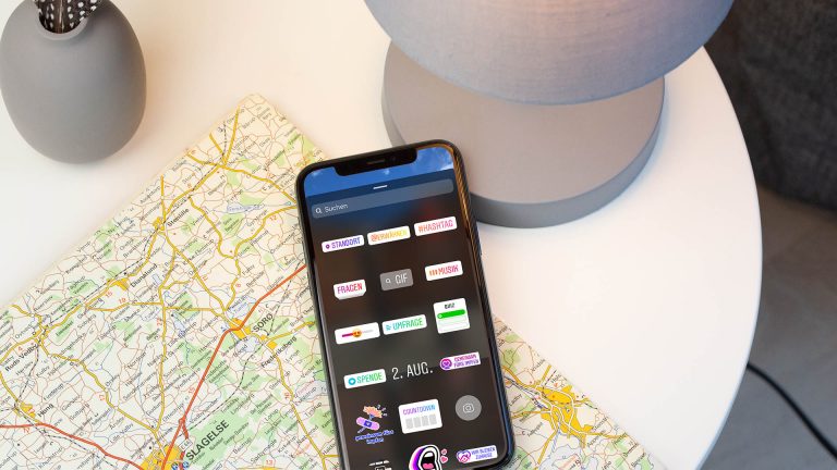 Ein iPhone liegt auf einer Landkarte. Auf dem Display sind die unterschiedlichen Sticker von Instagram zu sehen.