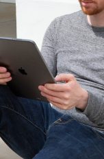 Eine Person sitzt auf einer Treppe. In den Händen hält sie ein iPad Pro.
