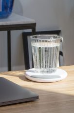 Auf einem Büroschreibtisch steht ein Wasserglas auf dem Beurer Trinkmanager.