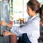 Eine Person untersucht die T&uuml;r eines K&uuml;hlschranks genau.