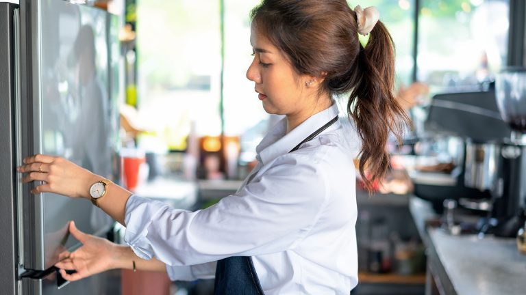 Eine Person untersucht die Tür eines Kühlschranks genau.