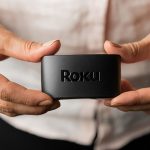 Eine Person h&auml;lt einen Roku Express in die Kamera.