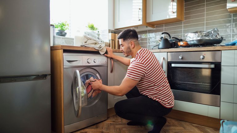 Eine Person bestückt die Waschmaschine mit Wäsche.