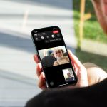 Eine Person hält ein iPhone in der Hand. Auf dem Bildschirm ist ein laufendes FaceTime-Gespräch zu sehen.