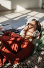 Digital-Analog-Converter Eine Person liegt auf dem Boden, liest etwas und hört dabei Musik über Kopfhörer.
