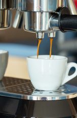 Kaffeemaschine Langsam läuft Espresso von einer Kaffeemaschine in eine kleine Espresso-Tasse.