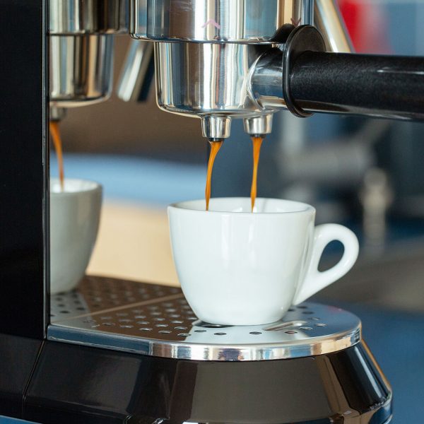 Langsam l&auml;uft Espresso von einer Kaffeemaschine in eine kleine Espresso-Tasse.