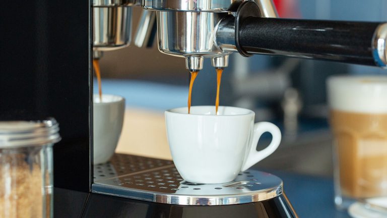 Langsam läuft Espresso von einer Kaffeemaschine in eine kleine Espresso-Tasse.