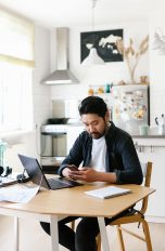 Günstige Laptops Eine Person sitzt an einem Tisch mit einem Laptop vor sich und arbeitet.