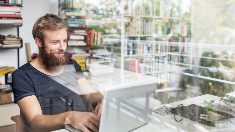 Eine Person sitzt an einem Laptop und tippt. Im Hintergrund sind B&uuml;cherregale zu sehen.
