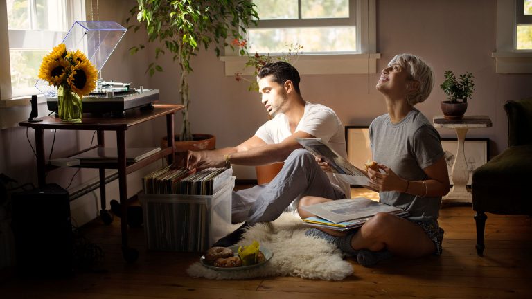 Zwei Personen sitzen auf dem Fu&szlig;boden vor einer Plattenkiste und schauen sich die Schallplatten an.
