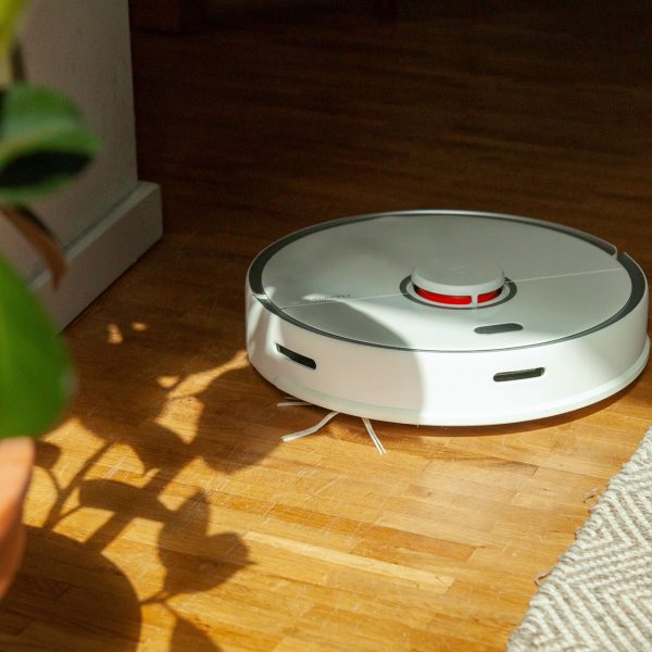 Ein Roborock f&auml;hrt durch eine Wohnung und reinigt einen Holzboden.