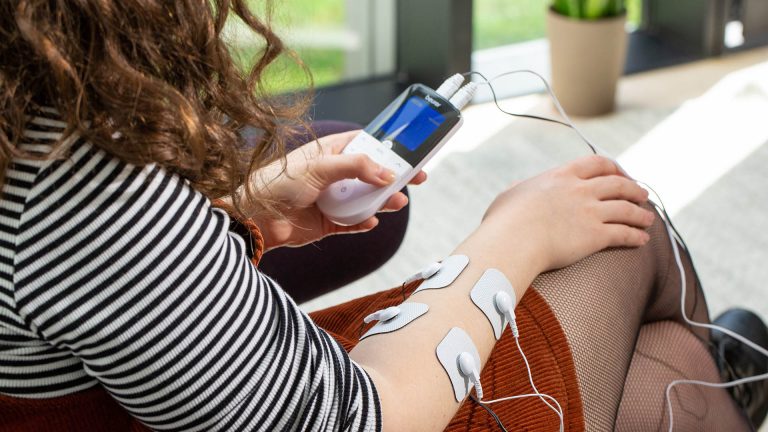 Eine Person wendet ein TENS-Gerät am Arm an.