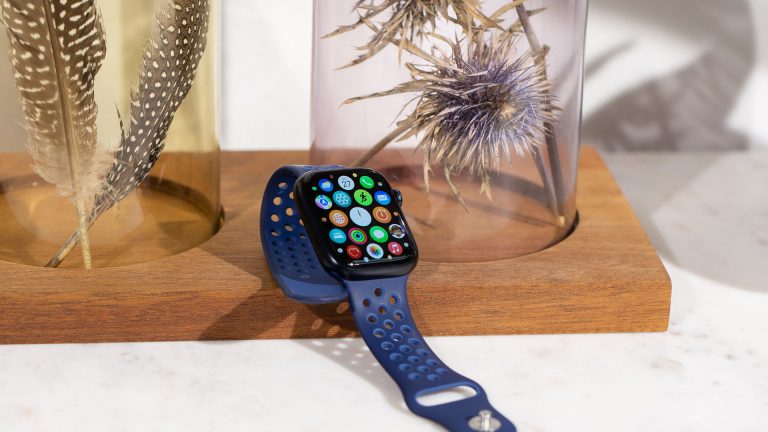 Eine Apple Watch 7 liegt auf einem Marmortisch, dahinter liegen eine Deko-Elemente.