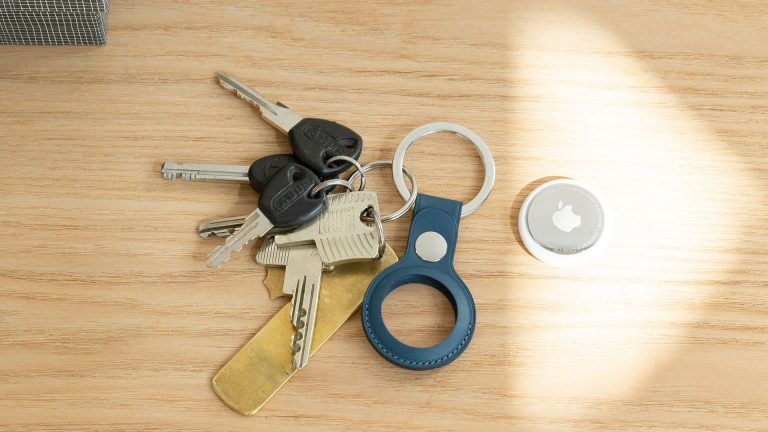 Ein Schlüsselbund liegt auf einem Holztisch, daneben ein Apple AirTag.