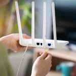 Eine Person schlie&szlig;t ein Ethernet-Kabel an einen Router an.