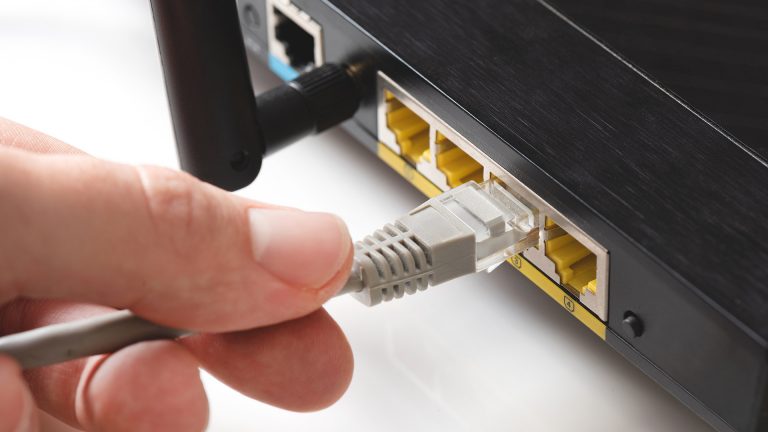 Eine Person steckt ein Ethernet-Kabel in einen Router.