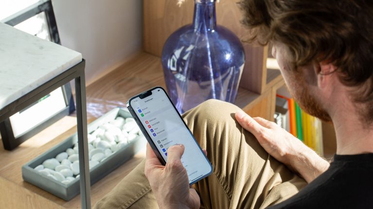 Eine Person h&auml;lt ein iPhone in der Hand, auf dem die Einstellungen zu sehen sind.