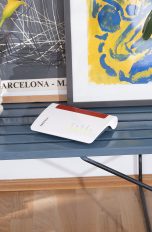 Fritzbox als WLAN-Repeater Eine Fritzbox steht auf einem Tisch vor einigen Bildern.