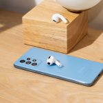 Ein paar AirPods liegt zusammen mit einem Android-Smartphone auf einem Tisch.