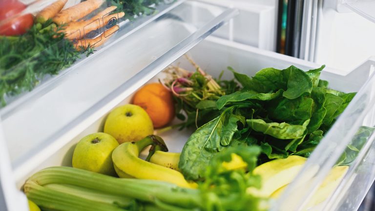 Nahaufnahme eines geöffneten und gut gefüllten Gemüsefachs in einem Kühlschrank.