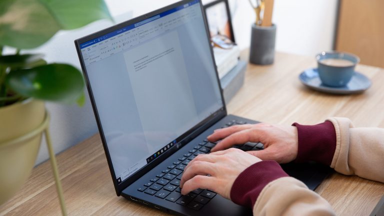 Eine Person tippt auf der Tastatur eines LG-Gram etwas in ein Text-Dokument.