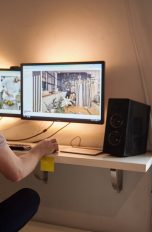 PC-Lautsprecher Eine Person sitzt vor zwei Bildschirmen. Daneben sind Lautsprecher zu sehen.