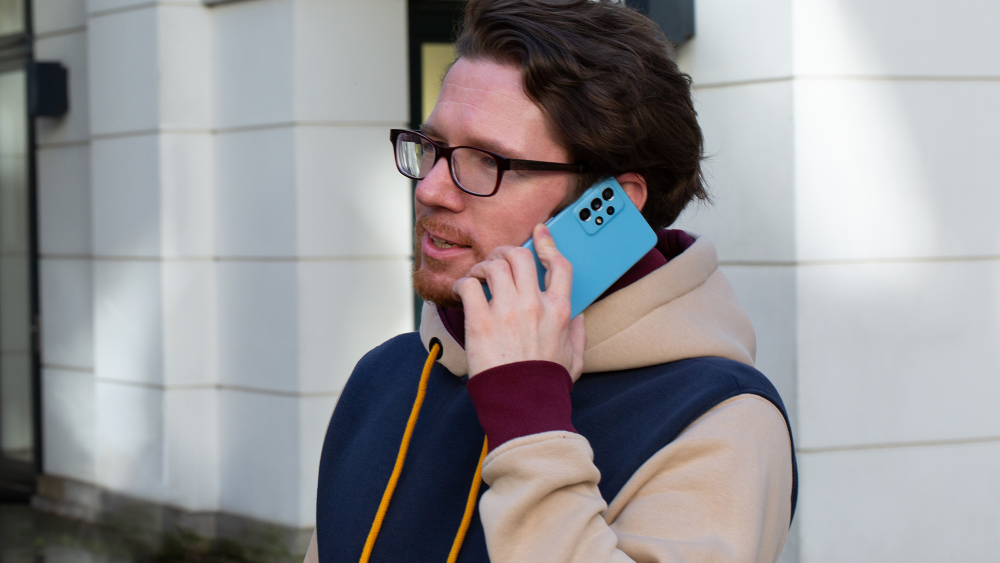 Eine Person hält sich ein Samsung Galaxy A52S ans Ohr, um zu telefonieren.