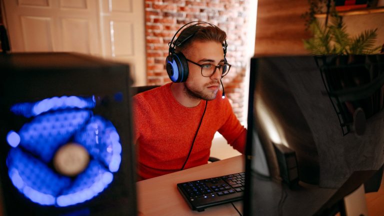 Eine Person mit einem Headset auf dem Kopf sitzt vor einem Gaming-PC.