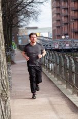 Eine Person läuft in der Speicherstadt in Hamburg an der Straße entlang und trägt dabei einen Fitnesstracker.