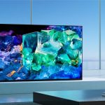 Ein Sony BRAVIA XR A95K steht auf einer TV-Bank vor einem gro&szlig;en Fenster.