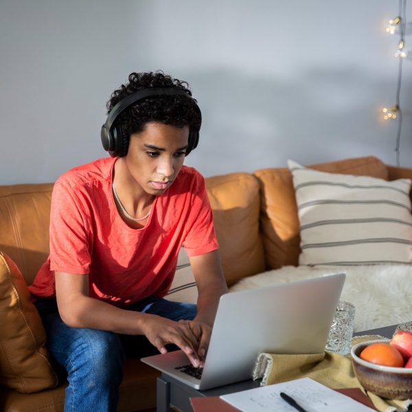 Eine Person mit Kopfhörern auf dem Kopf sitzt vor einem MacBook.