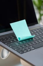 Auf der Tastatur eines MacBooks klebt ein türkisfarbener Post-it.