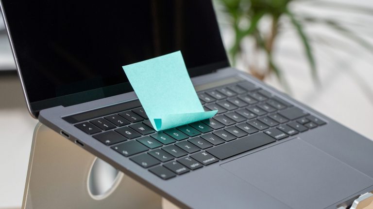 Auf der Tastatur eines MacBooks klebt ein türkisfarbener Post-it.